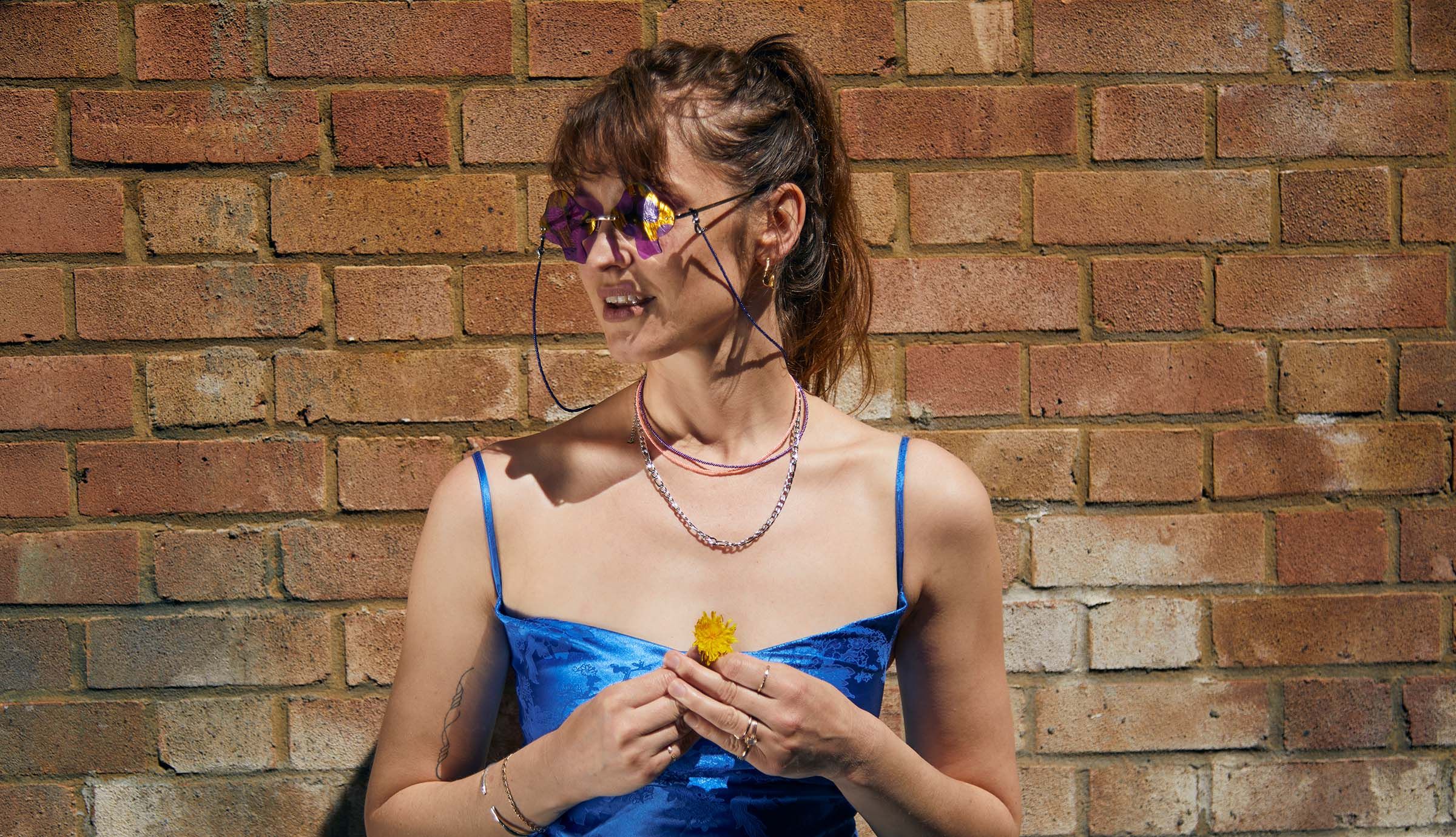 Model is wearing Figaro chain silver, luna flamingo and purple orchid bead necklace and celeste navy bead glasses chain